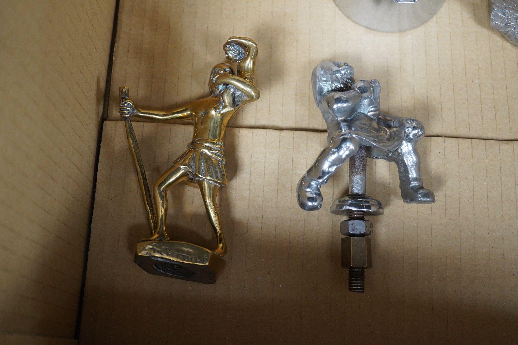 Seven chrome and brass car mascots, including two RAC logos, a head of Minerva, a crusader atop of a castellated pediment, a figure of Saint Christopher, a winged helmet, etc.